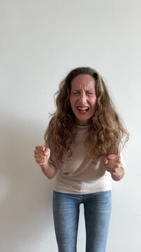 Mujer blanca gritando con pu&ntilde;os cerrados sobre fondo blanco