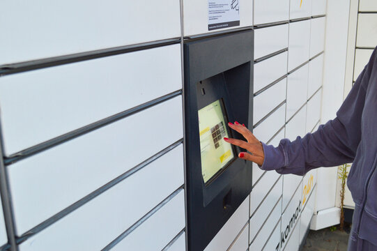 Person using InPost automated parcel locker touchscreen for package pickup in Poland