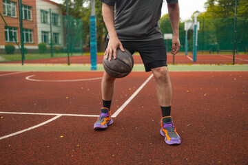 Fototapeta premium Action shot of a young man dribbling a ball on an outdoor basketball court during sunny day