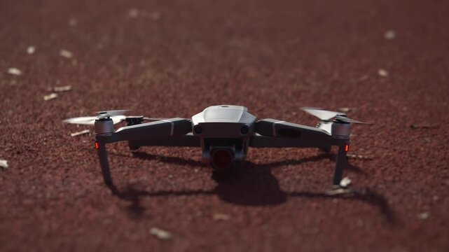 Drone lifting off from red outdoor athletic track in slow motion