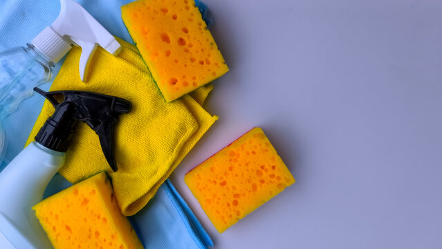 Top view of cleaning set with yellow sponges and blue wipes on a purple background.