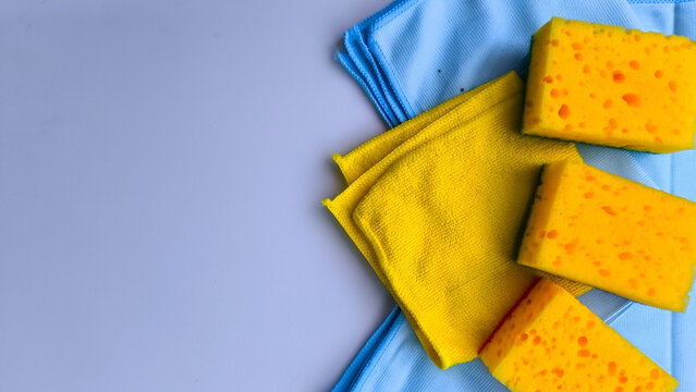 Color contrast cleaning set with yellow abrasive sponges and blue soft rags for various surfaces.