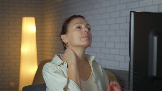 Tired overworked woman massaging her sore neck. Stressed office woman suffering from neck pain due to long hours of sedentary work at her computer desk, massaging her tired muscles to relieve