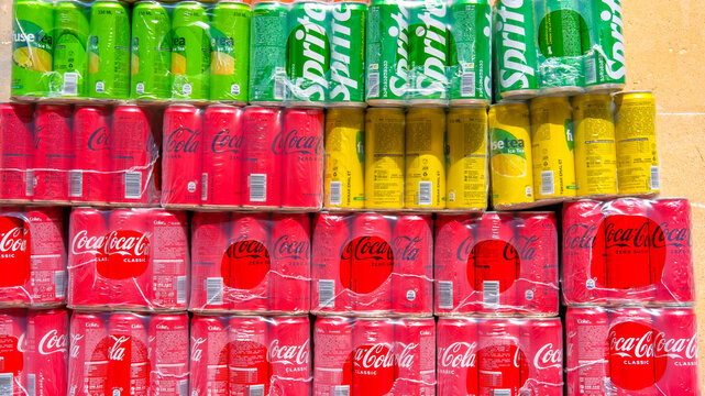 Baku, Azrbaijan - 05.01.2026: Coca-Cola Company beverages in aluminum cans. Stacked bulk in plastic shrink-wrap for wholesale or large-scale retail. Soda drinks delivery for cafes and supermarkets