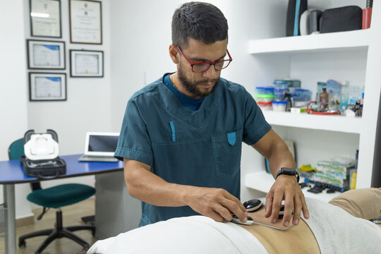 Wide view of a physiotherapist applying electrotherapy treatment to a female patient in a modern rehabilitation clinic. Healthcare, recovery, pain management and physical therapy concept.