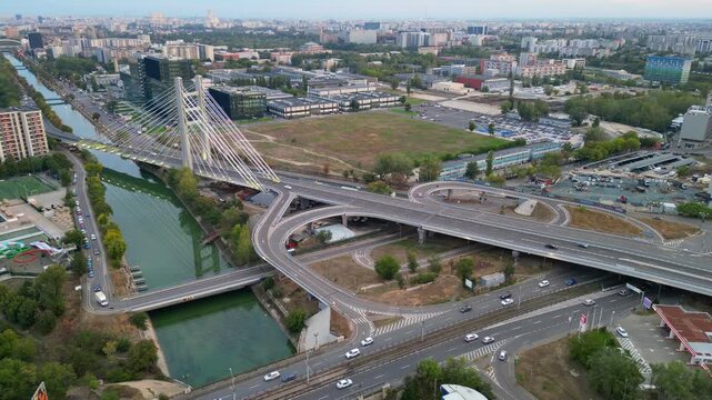 High angle twilight view of the modern Ciurel cable-stayed bridge in Bucharest, Romania. Scenic urban infrastructure with glowing traffic lights at sunset.