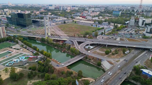 High angle twilight view of the modern Ciurel cable-stayed bridge in Bucharest, Romania. Scenic urban infrastructure with glowing traffic lights at sunset.