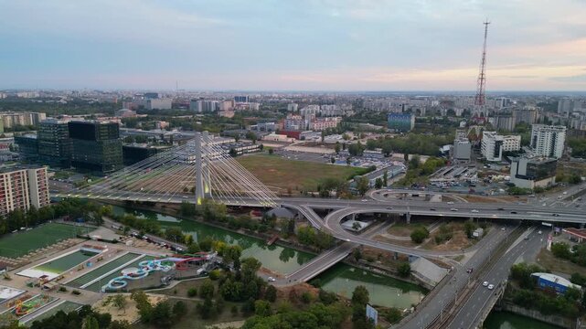 High angle twilight view of the modern Ciurel cable-stayed bridge in Bucharest, Romania. Scenic urban infrastructure with glowing traffic lights at sunset.
