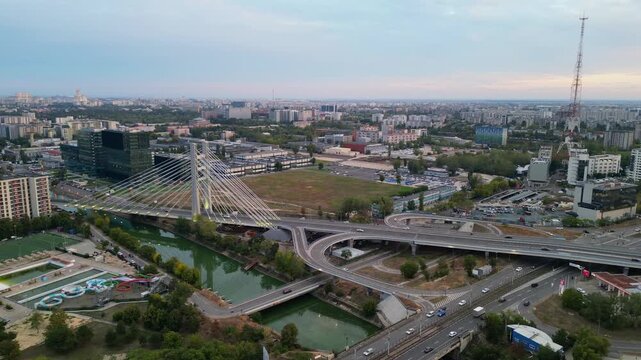 High angle twilight view of the modern Ciurel cable-stayed bridge in Bucharest, Romania. Scenic urban infrastructure with glowing traffic lights at sunset.