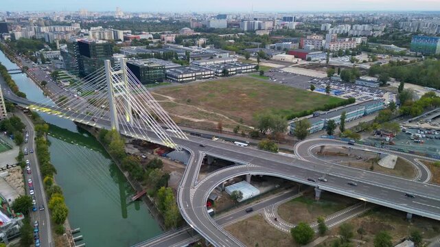 High angle twilight view of the modern Ciurel cable-stayed bridge in Bucharest, Romania. Scenic urban infrastructure with glowing traffic lights at sunset.