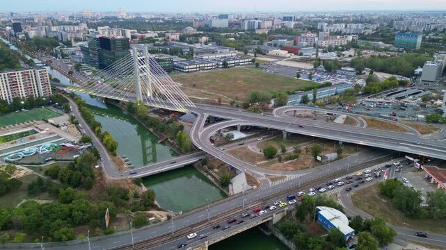 High angle twilight view of the modern Ciurel cable-stayed bridge in Bucharest, Romania. Scenic urban infrastructure with glowing traffic lights at sunset.