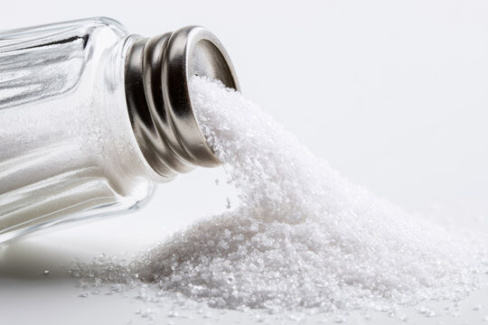 Salt shaker pouring salt on white background