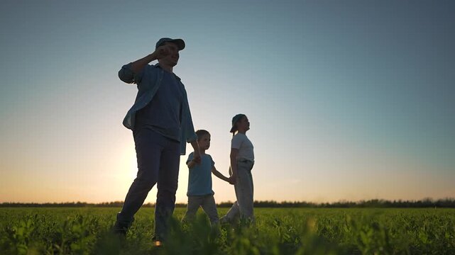Family walking holding hands in field. Silhouette father daughter son enjoy sunset together. Family together walk field sunset. Father daughter son smiling together. Happy family field walk together.