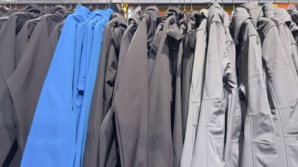 Row of sports jackets and workwear outerwear hanging on a rail with one bright blue coat standing out. © Alla