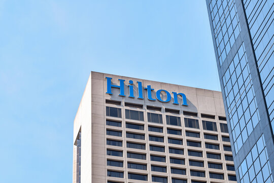 Minimal architectural view of the upper portion of a modern high rise building featuring a Hilton hotel sign in downtown Toronto against a clear sky, May 2026