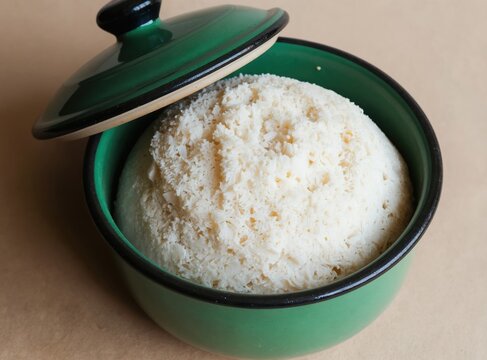 African maize meal, also known as pap, cooks in rustic green pot. Traditional staple food, carbohydrate rich porridge, nourishment for village community.