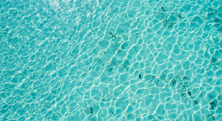 Obraz premium Crystal clear turquoise water surface with sunlight reflections and rippling waves.