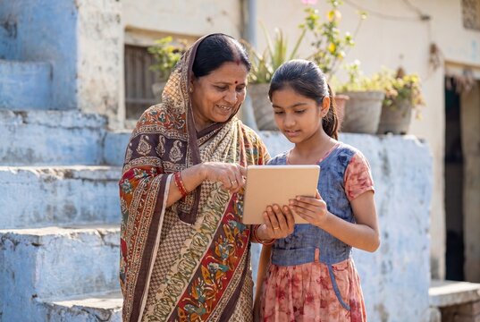 Elderly Indian Woman and Young Girl Using Tablet for Education in Rural Village
