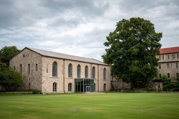 Obraz premium Historic Stone Building with Large Green Lawn and Mature Tree.