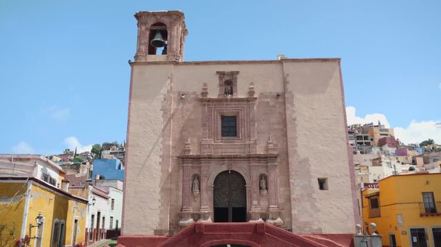 Guanajuato, Guanajuato Mexico; May 3 2026. San Roque square featuring the historic church architecture, iconic stone cross and tourist travelers walking at background street level 4K 29fps clip.