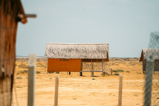 Traditional elevated mud house with thatched palm roof in arid desert landscape, La Guajira Colombia