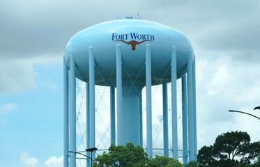Naklejka premium Northern Texas, U.S - May 27, 2026 - Light blue Fort Worth water tower with longhorn emblem supported by multiple columns under partly cloudy sky.
