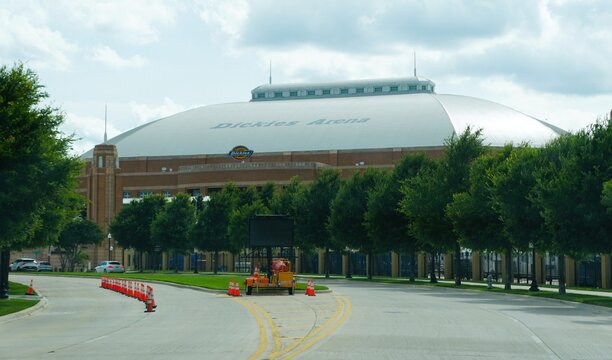 Fort Worth, Texas, U.S.A - May 27, 2026 - The Dickies Arena with domed roof, brick and metal exterior, traffic cones, and nearby roadway activity.
