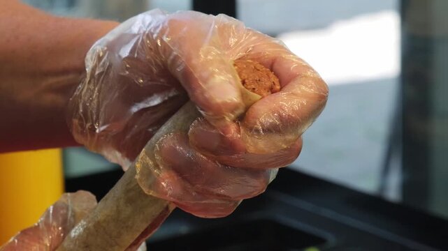 Close up video of a skilled chef pressing and shaping an innovative sushi roll made from traditional Turkish spicy cig kofte for a creative fusion dining experience.