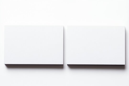 Two blank white square business cards lay side by side on clean white surface, casting subtle shadows below. Empty cards offer plenty of space for text graphics, perfect for branding, contact