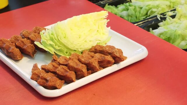 A close up video of an authentic chef hand squeezing traditional cig kofte portions with expertise and neatly arranging them on a serving plate, showing skilled Turkish culinary art.