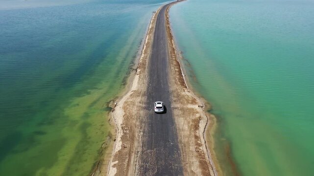 Car driving on narrow road between turquoise lakes