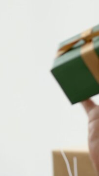 Vertical video: Reaching hand picking up green gift, woman inspecting ribbon and smiling, towel