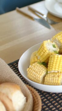 Vertical video: Panning cam right, corn bowl moving across table, revealing bread basket and fork