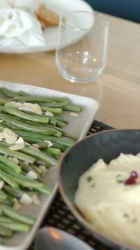 Vertical video: Panning camera over bean tray with almond at wood table, revealing mash, copy space