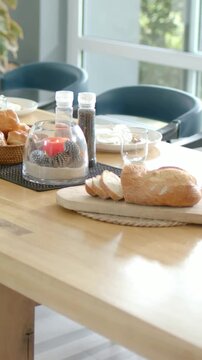 Vertical video: Panning camera showing sliced loaf on wood board at dining nook revealing brunch