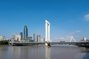 Obraz premium Modern Cable-stayed Bridge Over Urban River Under Clear Blue Sky