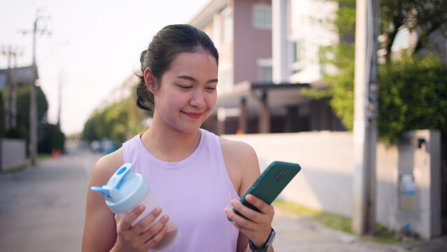 Young active woman drink whey protein shake bottle eating diet food using phone calorie AI plan app after workout health care asia people happy relax anti aging life weight loss public green park walk