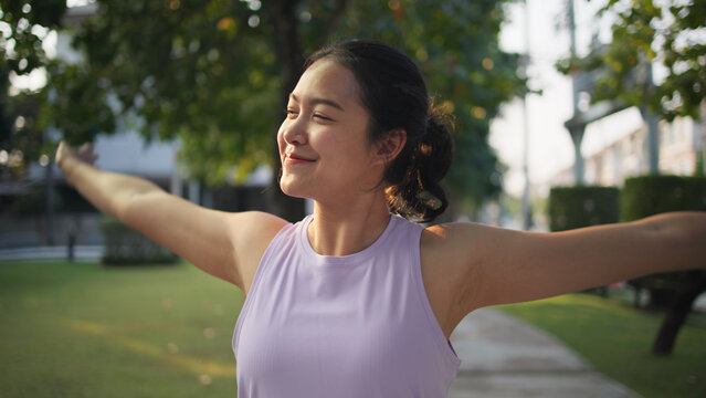 Asia young Gen Z people mindful happy woman open arm relax body deep stress relief outdoor nature green public park sun light self love anti aging life asian female mental health care modern medical.