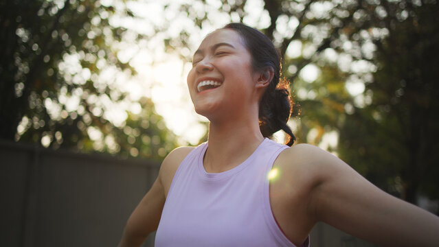 Asia young Gen Z people mindful happy woman open arm relax body deep stress relief outdoor nature green public park sun light self love anti aging life asian female mental health care modern medical.