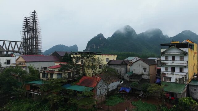 Cloudcovered Settlement Amidst Rocky Terrain. Misty Settlement Nestled Among Limestone Peaks And Moist Alleyways. Town Is Enveloped In Fog With Craggy Rocks Surrounding It And Humid Lanes
