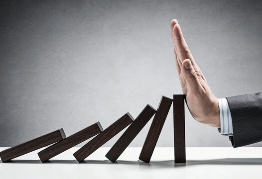 Business continuity and risk management concept, a hand stopping falling wooden blocks to prevent domino effect, crisis control, intervention, strategy, resilience, success, stop disaster, stability, 