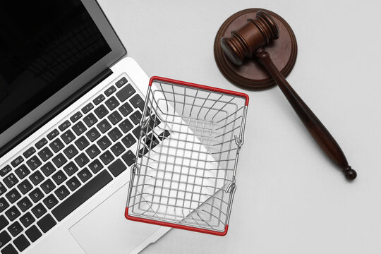laptop with shopping basket and auction gavel on light background