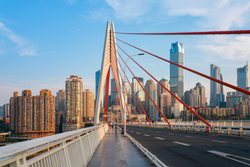Fototapeta premium Pedestrian walkway on Qiansimen Bridge leading to the white pylon and Jiefangbei skyscrapers skyline in Chongqing, China