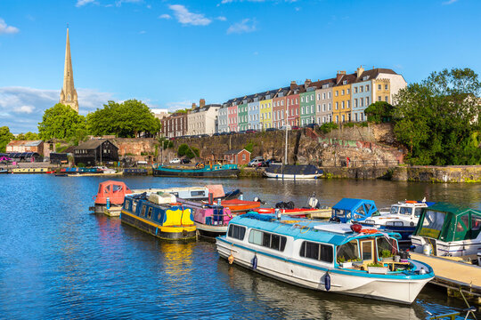 Colorful houses and narrowboats on Bristol Harbour with St Mary Redcliffe Church in Bristol, England, UK