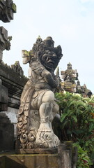 Fototapeta premium Giant statues, also known as bhuta kala, Dwarapala, gatekeeper statues carrying cups, torches, and weapons, with frightening faces. They wear Balinese poleng cloth. Photo raw, no edit.