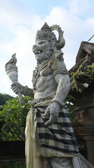 Obraz premium Giant statues, also known as bhuta kala, Dwarapala, gatekeeper statues carrying cups, torches, and weapons, with frightening faces. They wear Balinese poleng cloth. Photo raw, no edit.