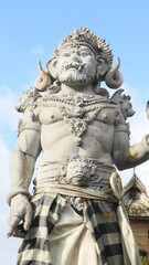 Obraz premium Giant statues, also known as bhuta kala, Dwarapala, gatekeeper statues carrying cups, torches, and weapons, with frightening faces. They wear Balinese poleng cloth. Photo raw, no edit.