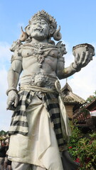 Fototapeta premium Giant statues, also known as bhuta kala, Dwarapala, gatekeeper statues carrying cups, torches, and weapons, with frightening faces. They wear Balinese poleng cloth. Photo raw, no edit.