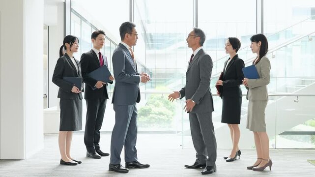 ロビーで握手する幅広い世代の男女ビジネスパーソンのグループ