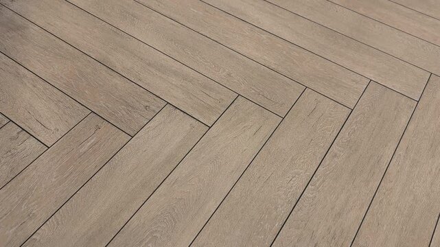 Elegant brown ceramic floor tiles are meticulously arranged in a classic herringbone pattern. The camera smoothly pans across the textured surface, highlighting the sophisticated interior design.